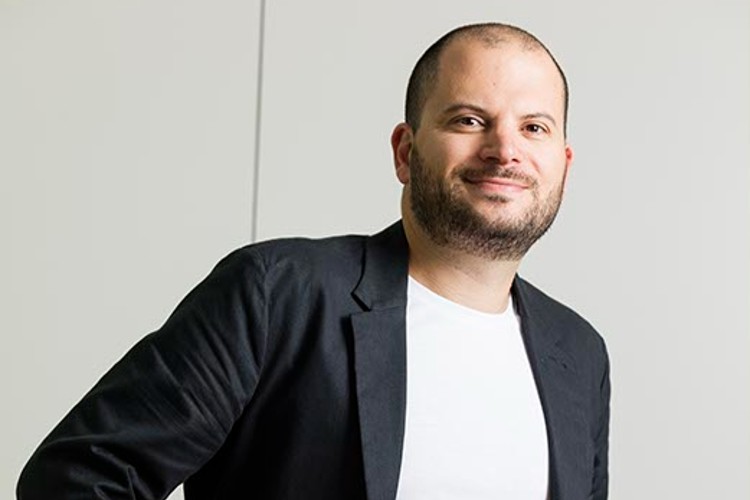 Smiling bald man in black blazer and white shirt