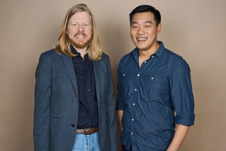 Two smiling men posing against neutral background