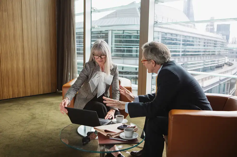 Two business professionals discussing laptop in office lounge