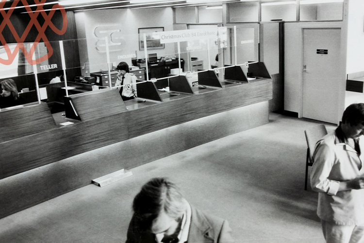 Black-and-white bank interior with teller counters and customers