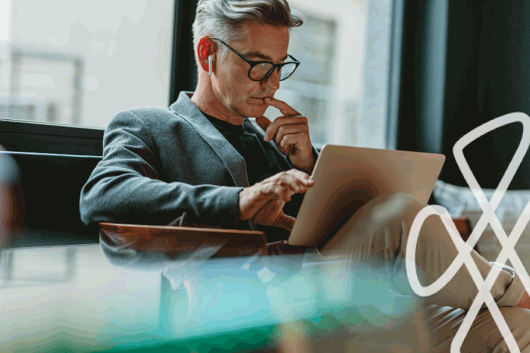 Man with glasses using laptop and earbuds indoors