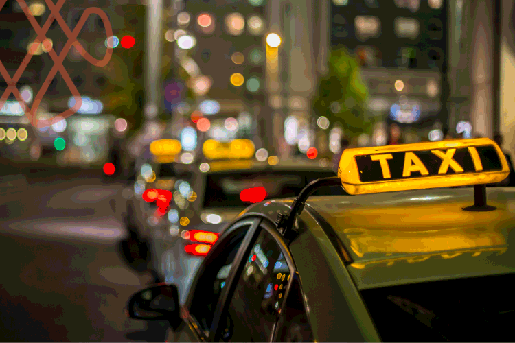 Yellow taxi sign on car at night city street