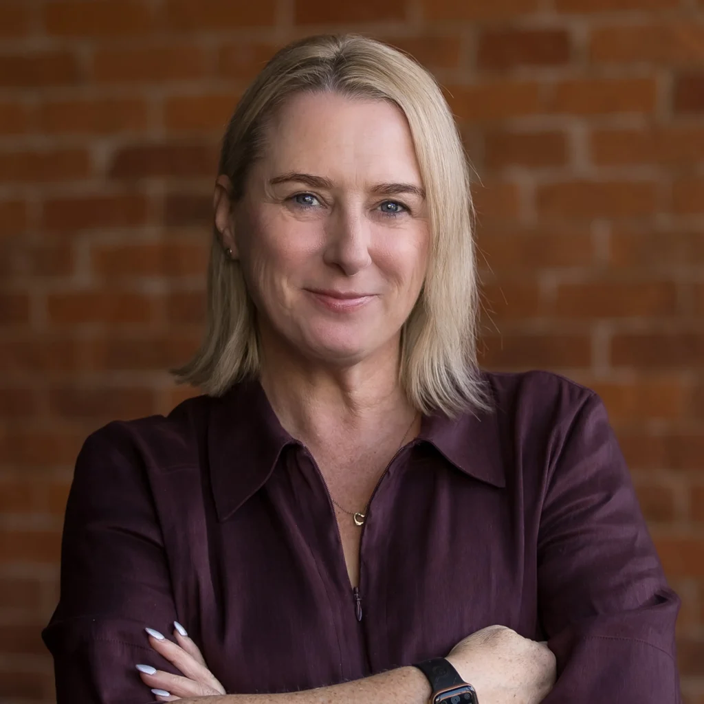 Professional portrait of smiling woman against brick wall