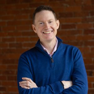 Professional portrait of smiling man against brick wall