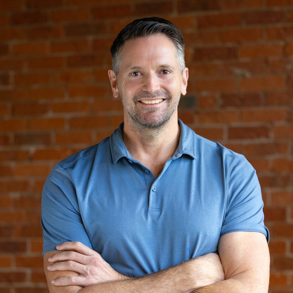 Professional portrait of smiling man against brick wall