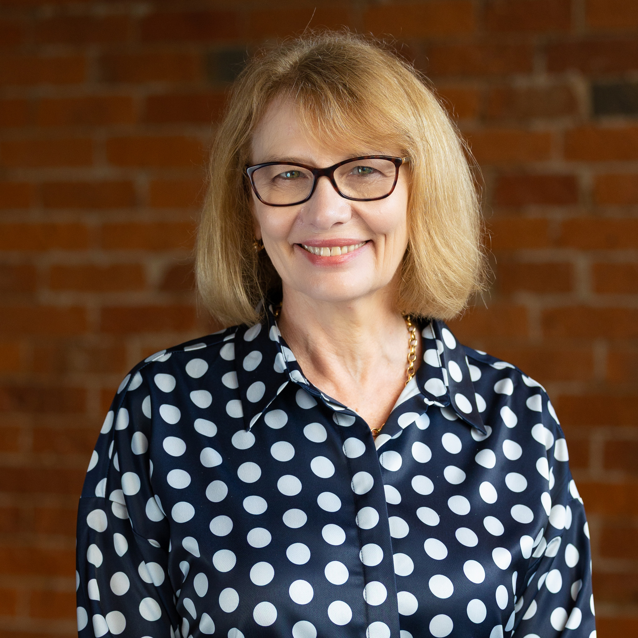 Professional portrait of smiling woman against brick wall