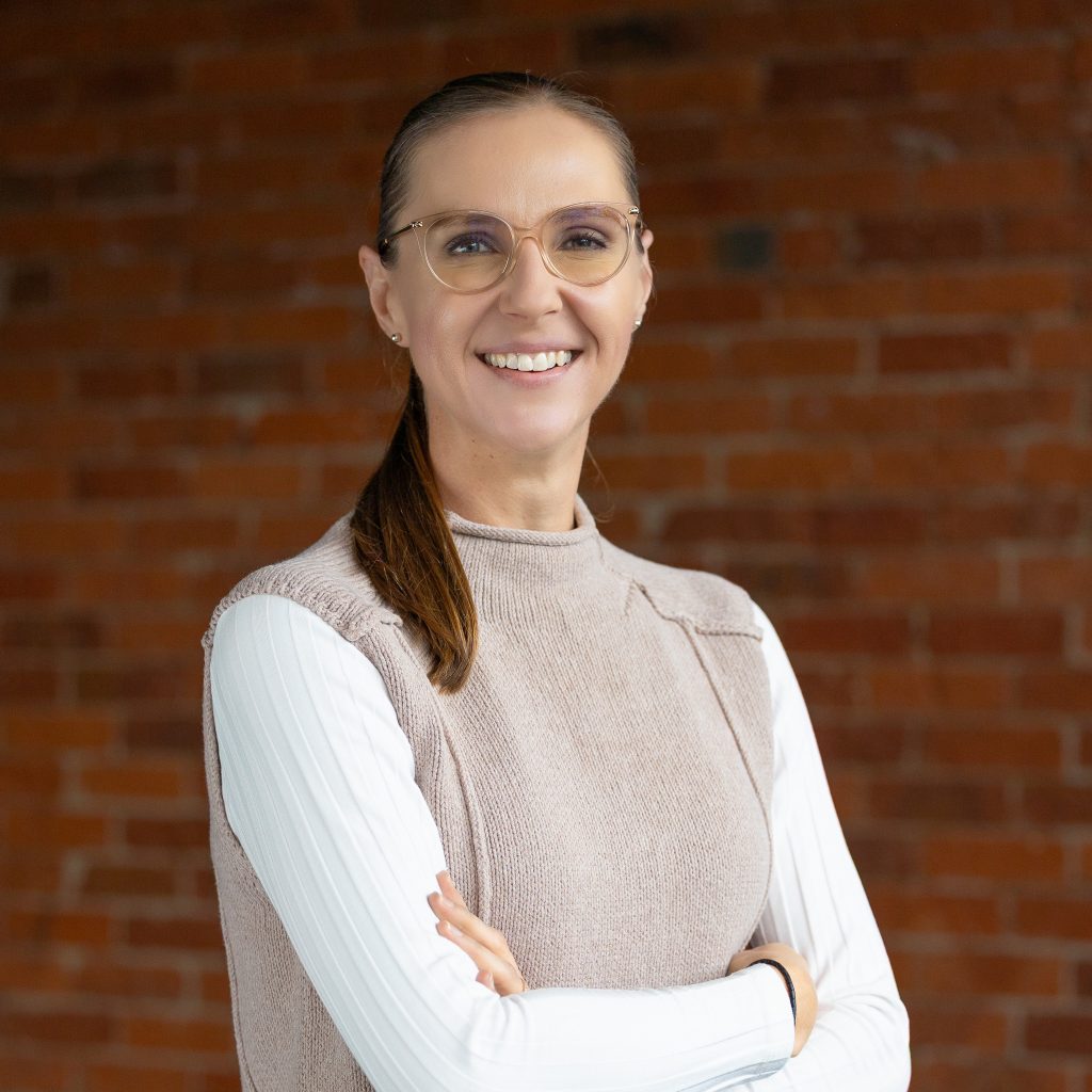 Professional portrait of smiling woman against brick wall