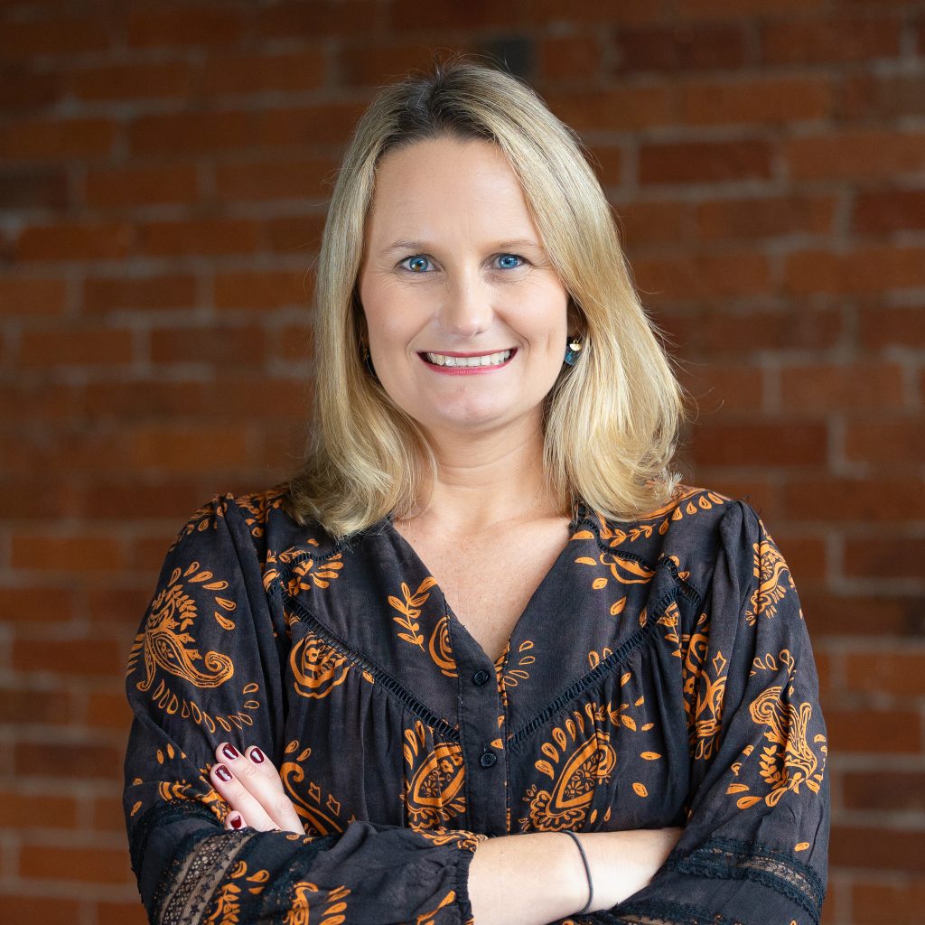 A professional portrait of smiling woman against brick wall