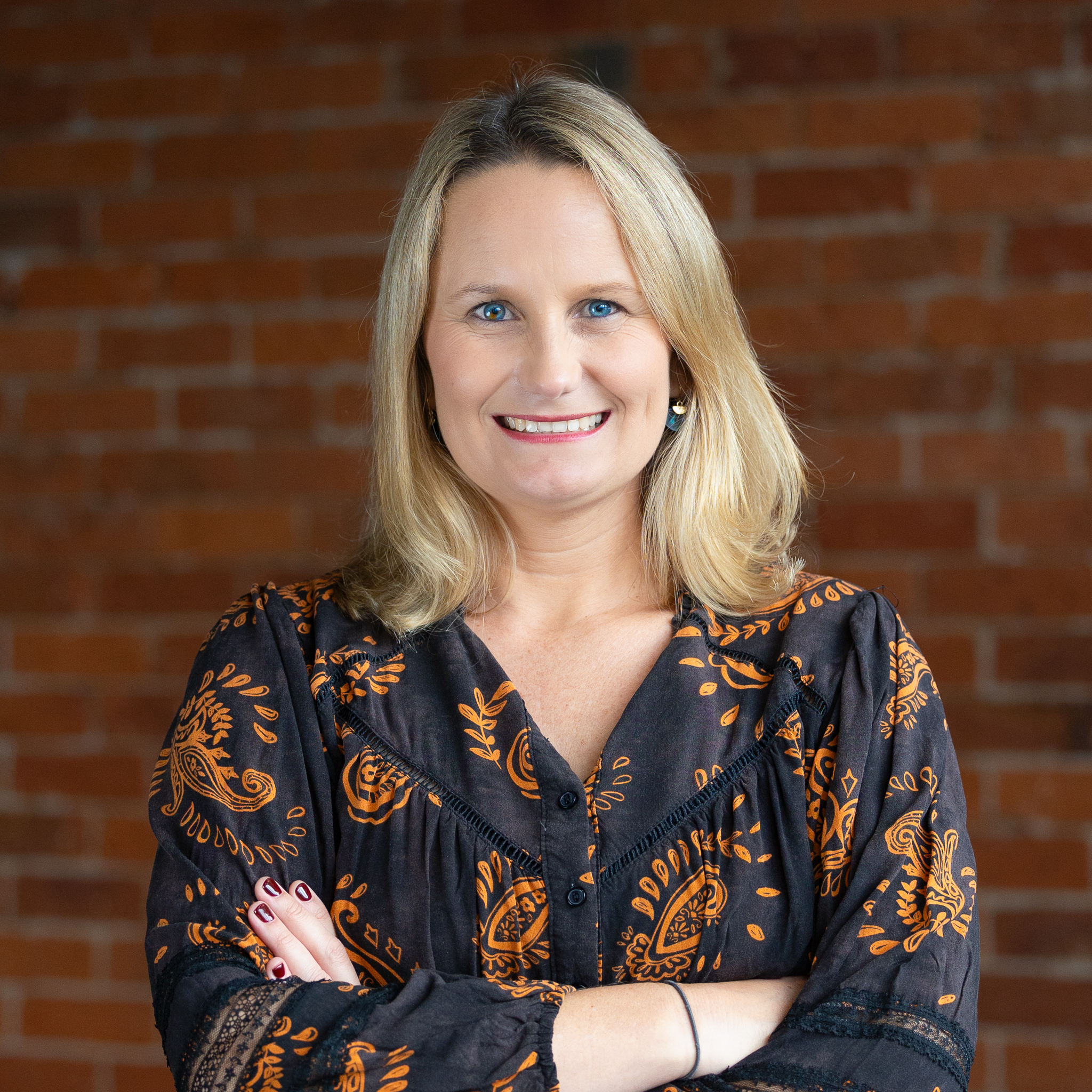 A professional portrait of smiling woman against brick wall