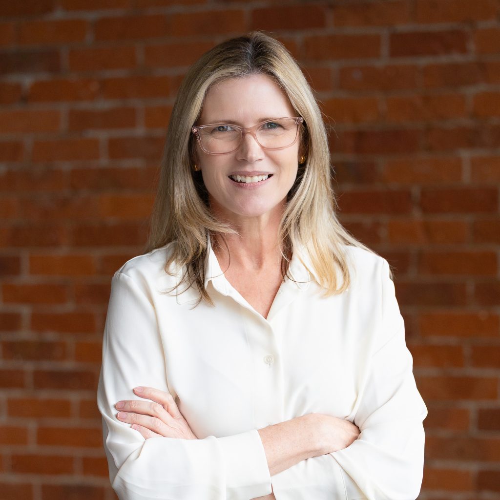Professional portrait of smiling woman against brick wall