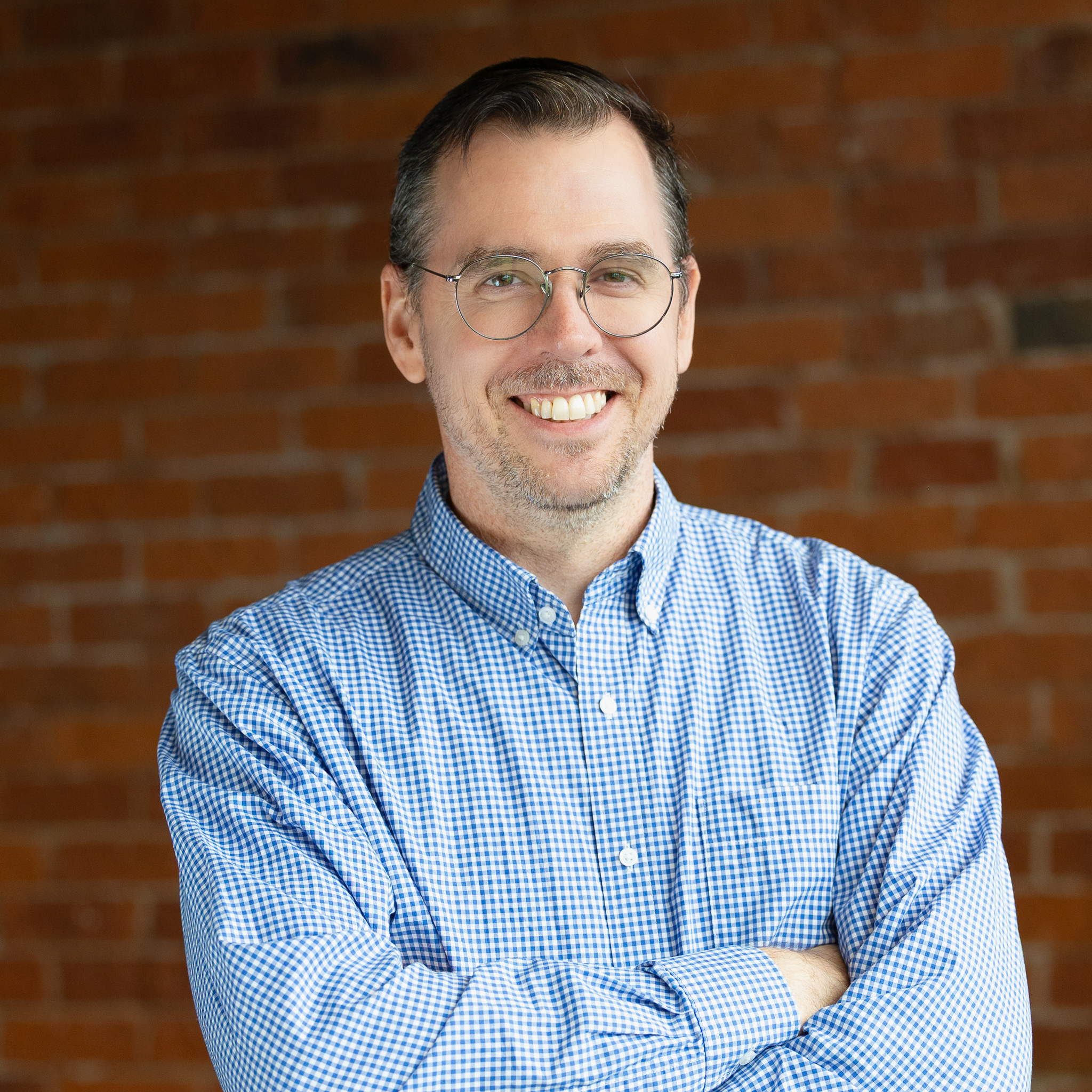Professional portrait of smiling man against brick wall