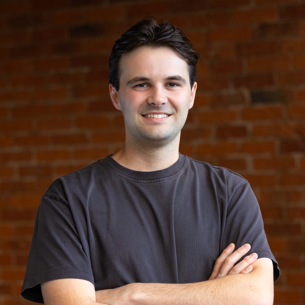 Professional portrait of a smiling man against brick wall