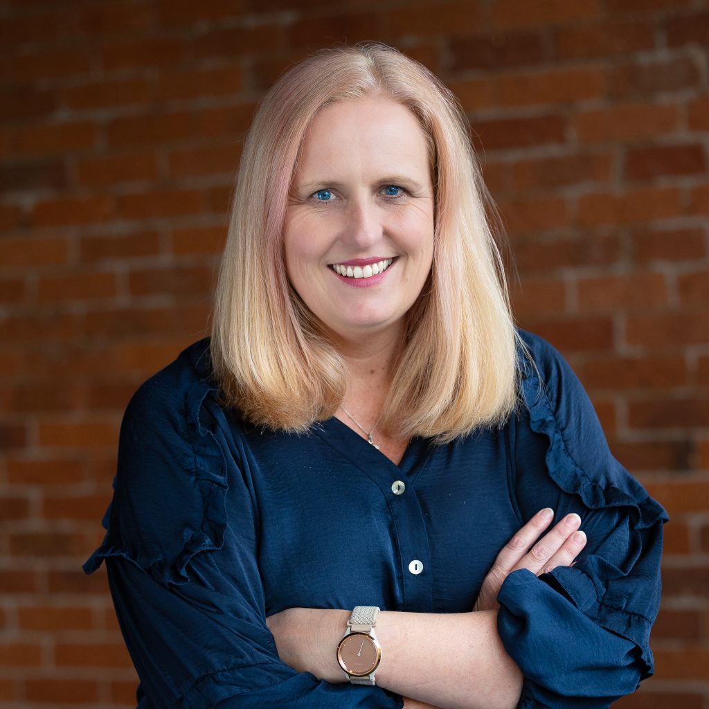 Professional portrait of smiling woman against brick wall