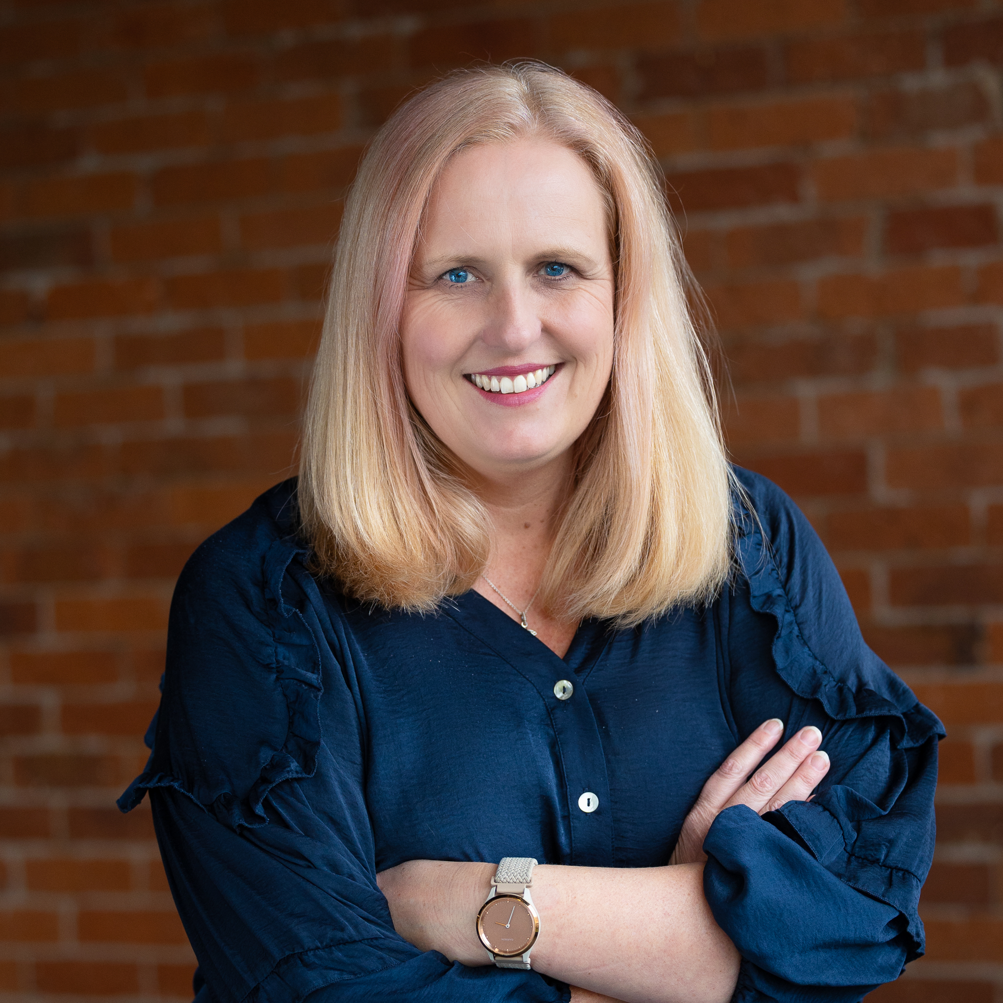 Professional portrait of smiling woman against brick wall