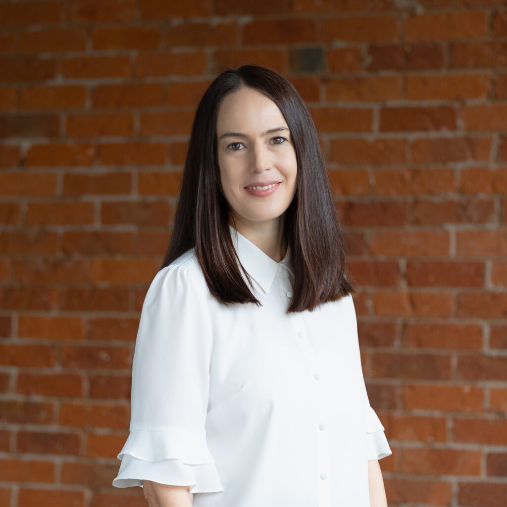 Professional portrait of smiling woman against brick wall