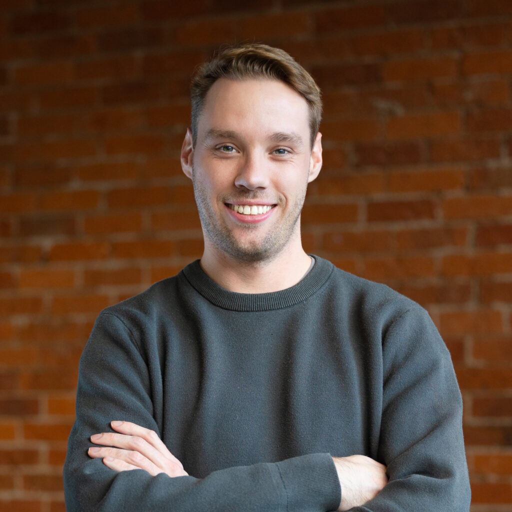 Professional portrait of smiling man against brick wall