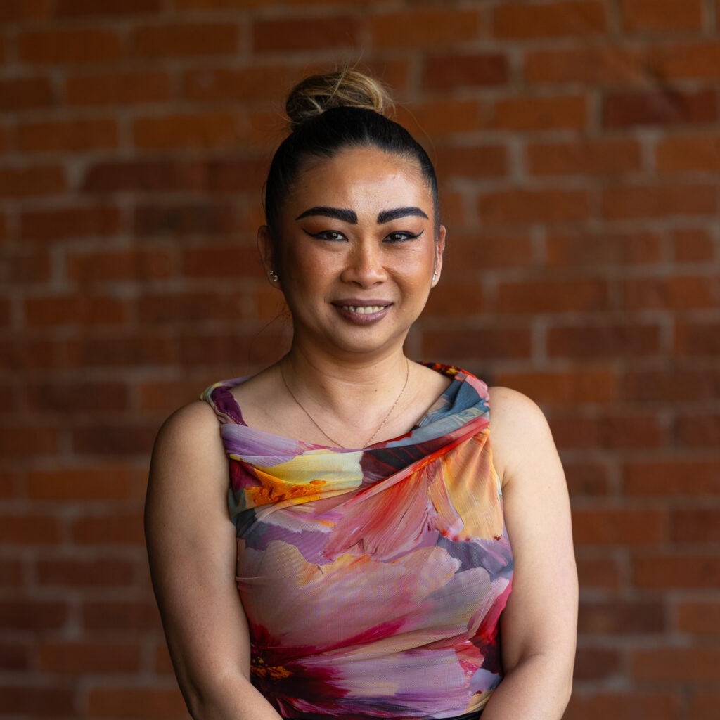 Professional portrait of smiling woman against brick wall