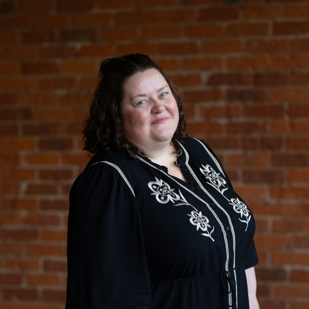 Professional portrait of smiling woman against brick wall
