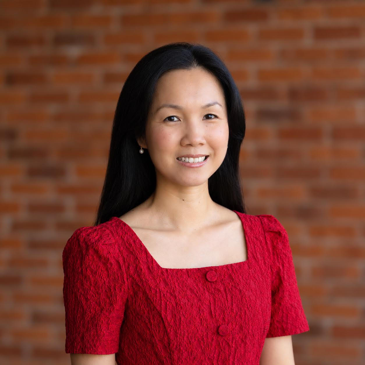 Professional portrait of smiling woman against brick wall